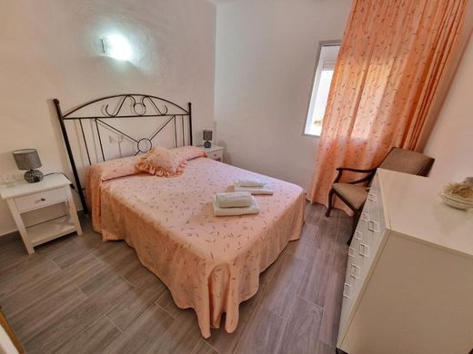 Dormitorio con cama doble de cabecero de forja y colcha estampada