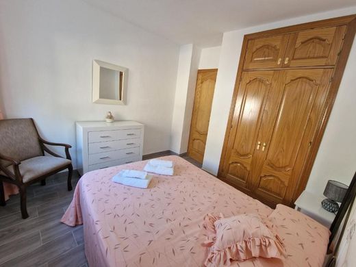 Mismo dormitorio con armario de madera, cómoda y sillón